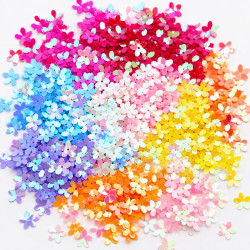 Iridescent flower-shaped sequins 10mm in a full colour mix – fuchsia, red, pink, white, blue, purple, yellow and orange AB – scattered in a rainbow arrangement on a white background